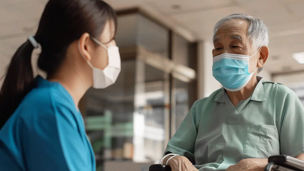 nurse talking to patient with infection control measures in place