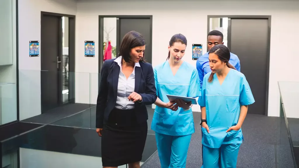 Nurse and staff huddle in hospital with custom door entry patient boards 