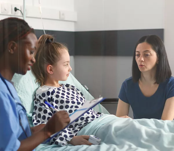 Nurse caregiver discussing care of pediatric patient in patient room with custom VisiCare Plexi Board featuring superhero characters
