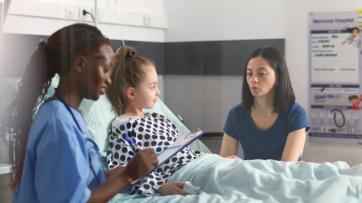 Nurse caregiver discussing care of pediatric patient in patient room with custom VisiCare Plexi Board featuring superhero characters