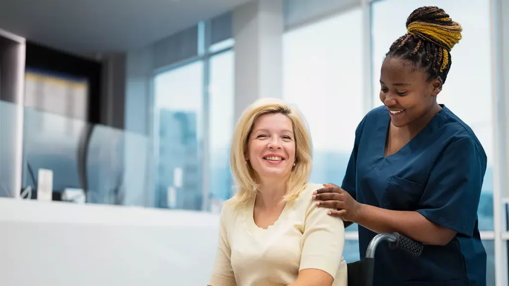 Nurse actively listening to patient in transport through hospital lobby with nurse unit custom communication board 