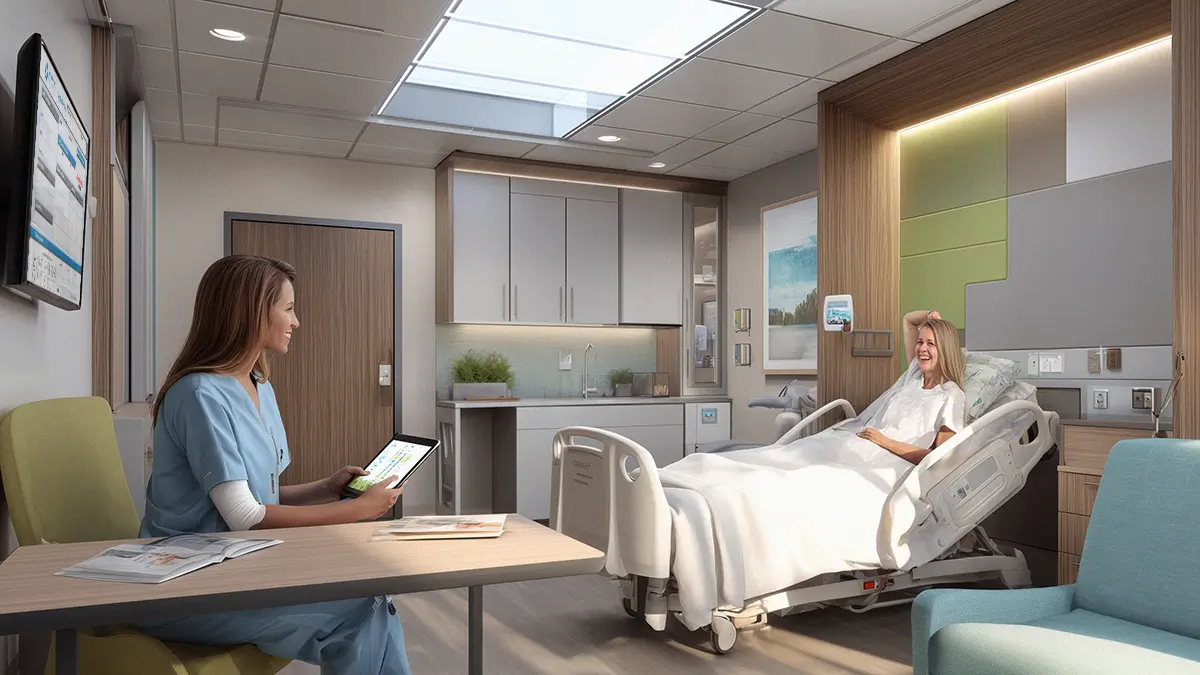 high end patient room where nurse with tablet is discussing care with female patient in hospital bed sitting across froma patient an electronic VisiCareHD Digital Board