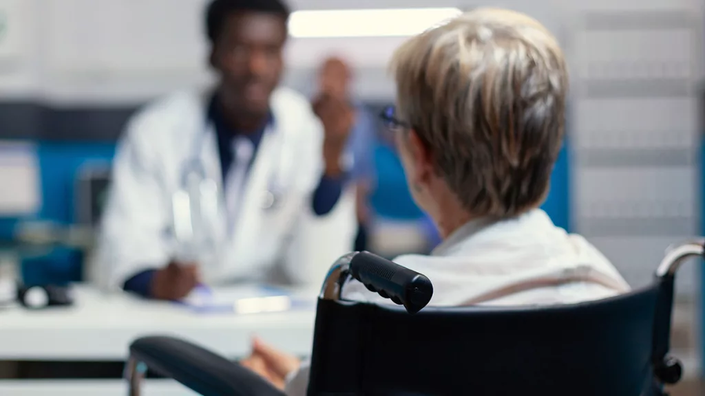 Selective focus on sick senior patient with disability talking with physician about illness.