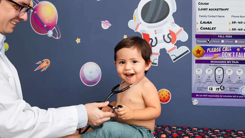 Doctor and pediatric patient in space themed patient room with custom dry erase Glass Hybrid Board style