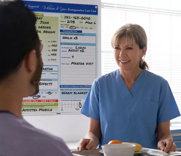 Nurse and patient discuss dietary in hospital room with custom VisiCare Patient Board for Post Op