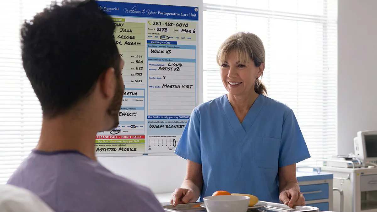 Nurse and patient discuss dietary in hospital room with custom VisiCare Patient Board for Post Op