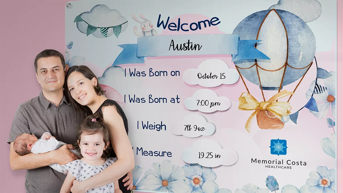 family poses for photo in front of celebration board at hospital