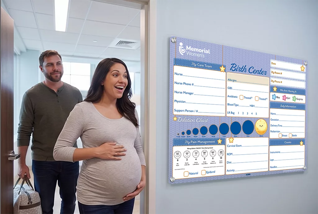 Expecting mother walks into birthing suite with custom Labor Delivery patient board