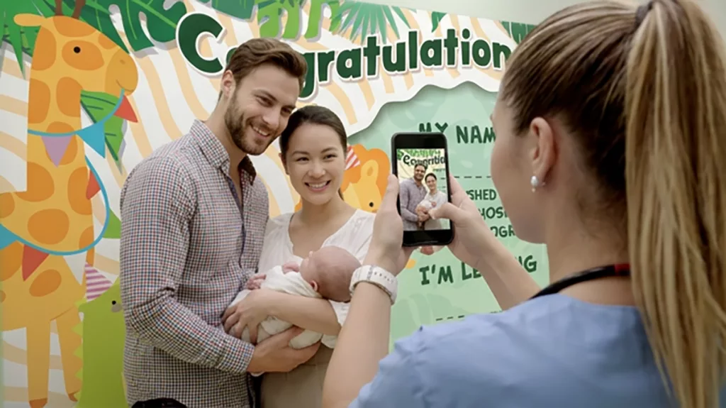 Nurse snaps photo infront of custom Celebration Board for new family discharging from 5 star hospital